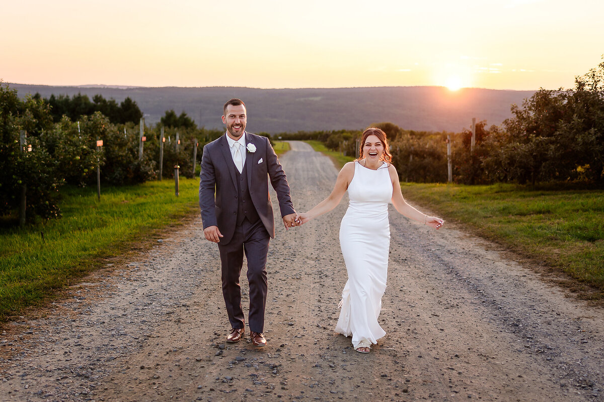 Bride and groom walking down dirt road at Alyson Orchard