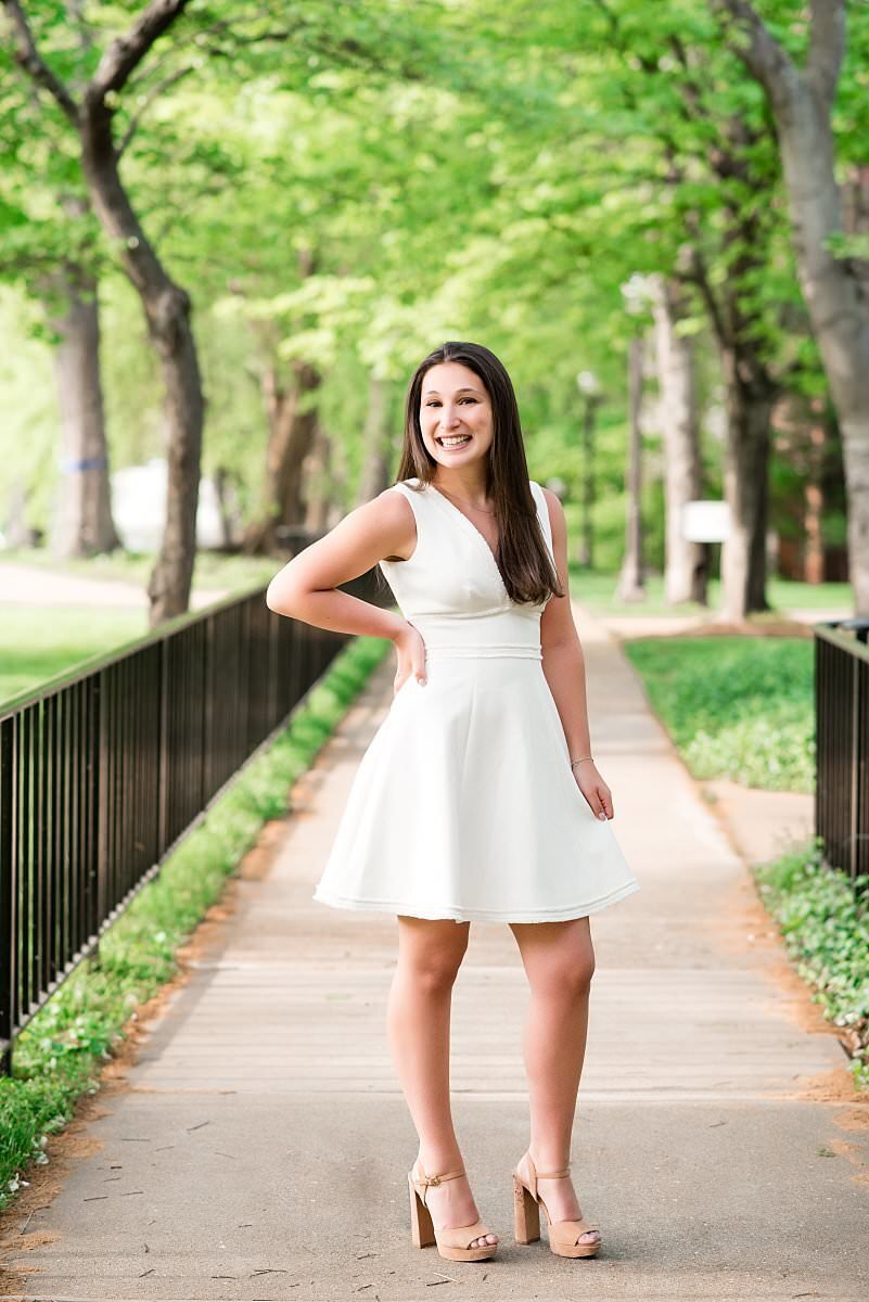 Girl wearing white dress and smiling with her hand on her hip