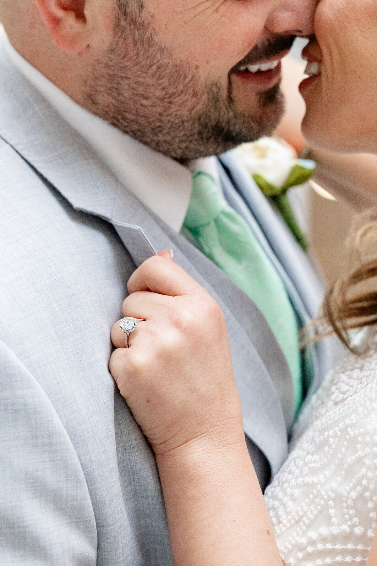 Close-up shot of the bride and groom about to kiss, with focus on the bride’s sparkling engagement ring.