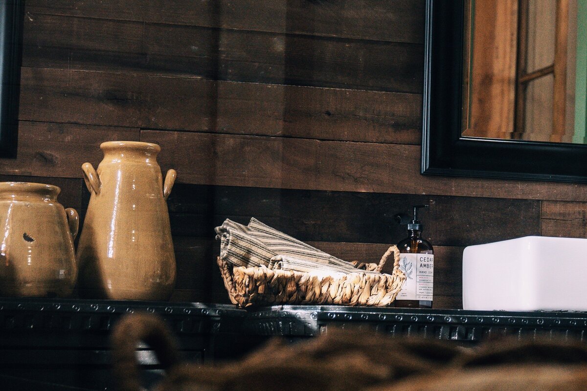 black bathroom furniture sink base with white vessel with brass water faucet and mustard pottery vessels on top of the vanities