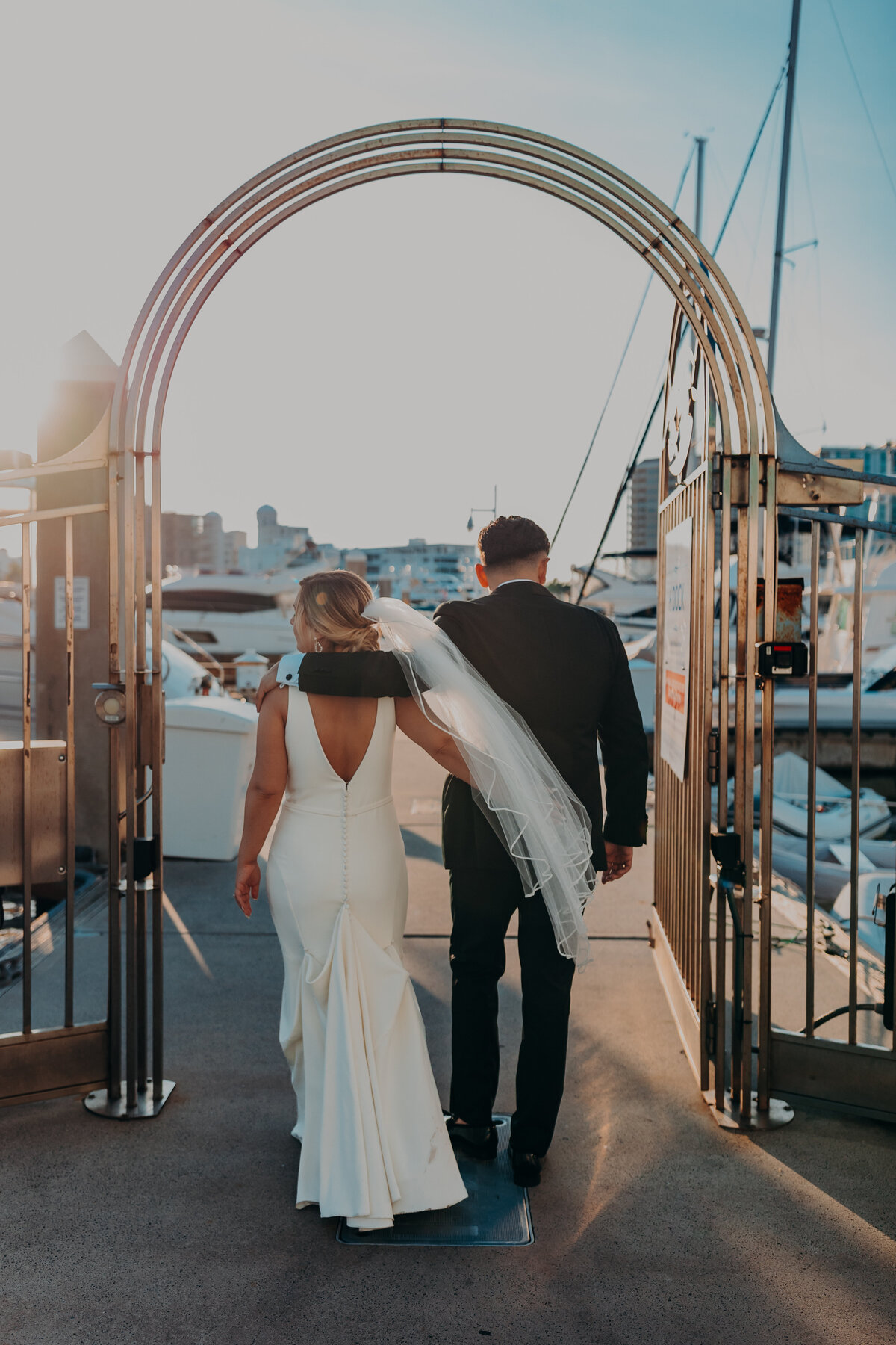 A bride and groom take portraits on the docks at Marina Jacks, a wedding venue in Sarasota, Florida during sunset, golden hour- by Angela Moon Photography. 