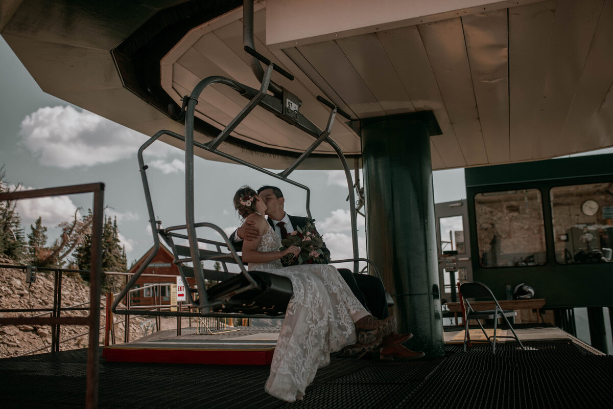 bride adn groom sitting together on a sky ride as they ride together to their mountain top ceremony in the Tetons