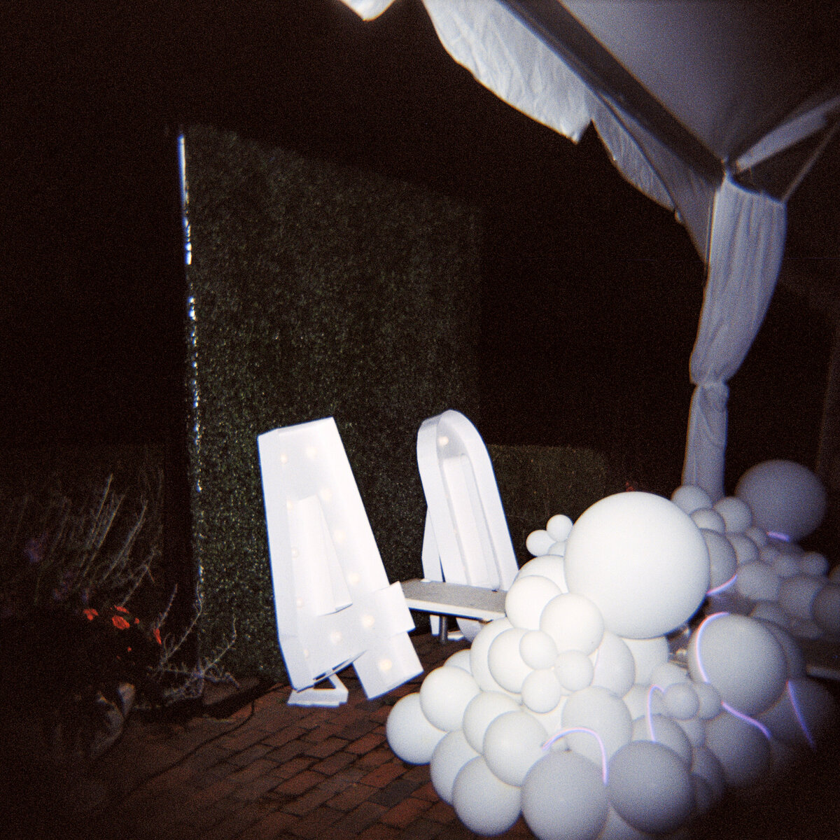 Photo of white balloons and 4-0 lights on film in private backyard party by Mira Park Photography NY based wedding photographer