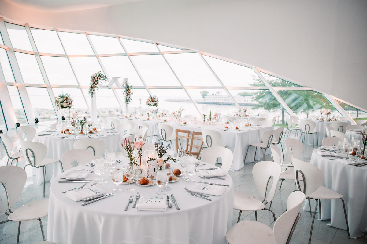 A white wedding reception set up with pink florals at the Milwaukee Art Museum
