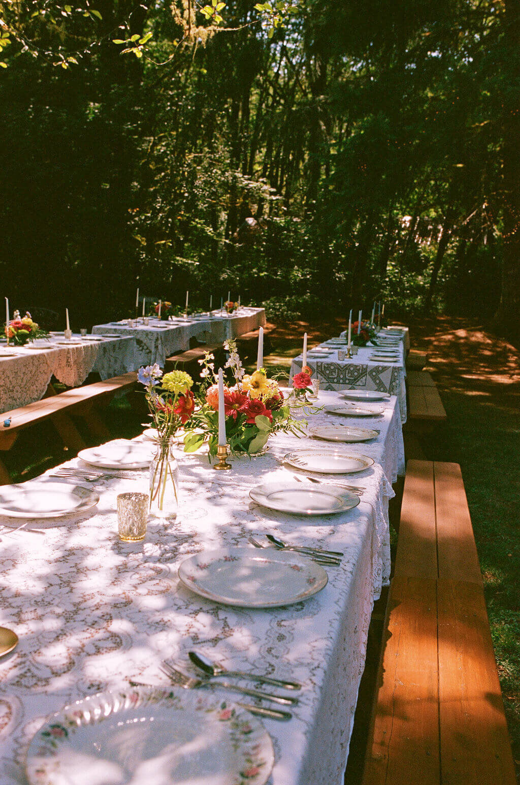 Wooden tables set at an outdoor wedding using rented tableware from Birdie June Rentals.