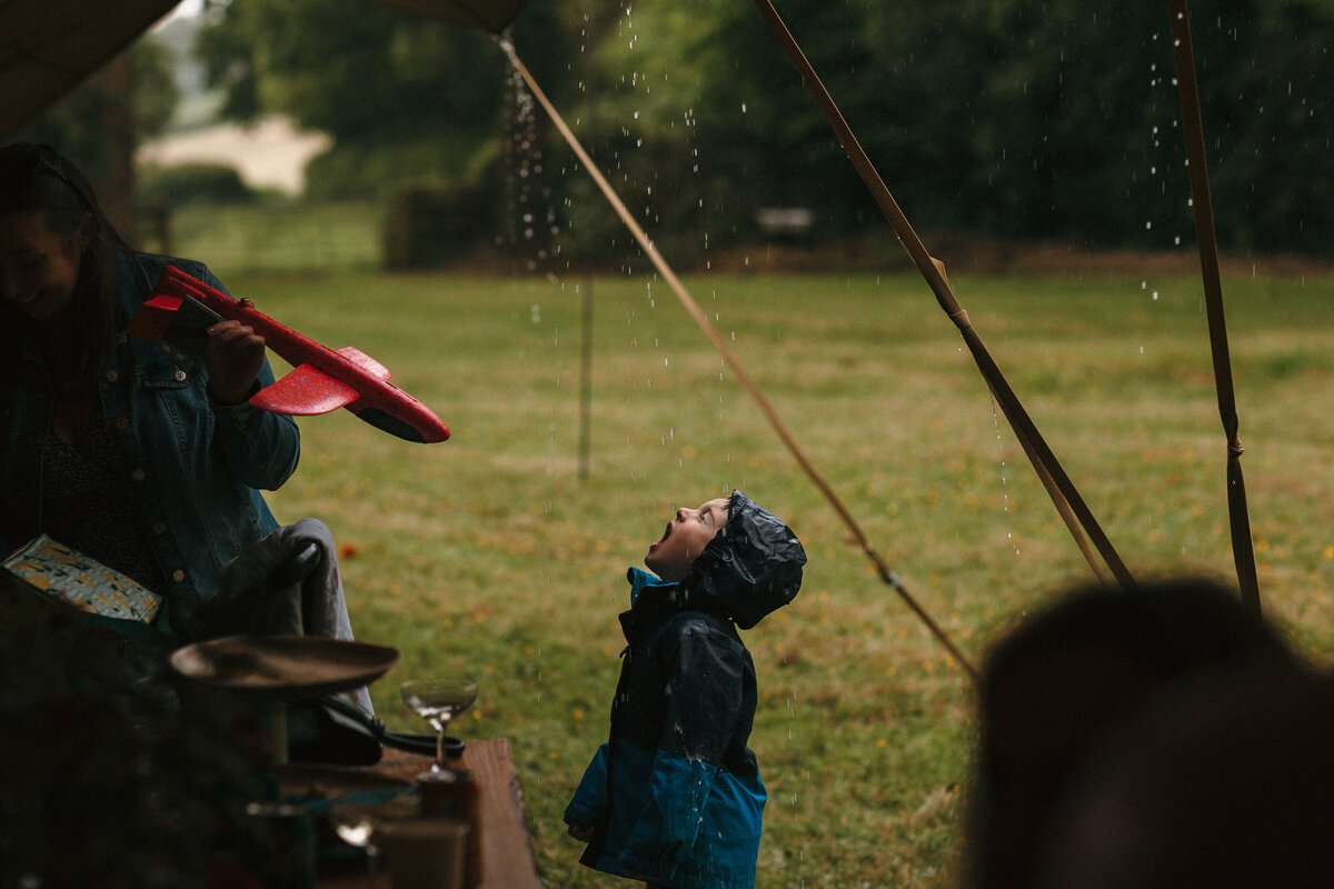 boy drinks rain from drips of tipi at a wedding