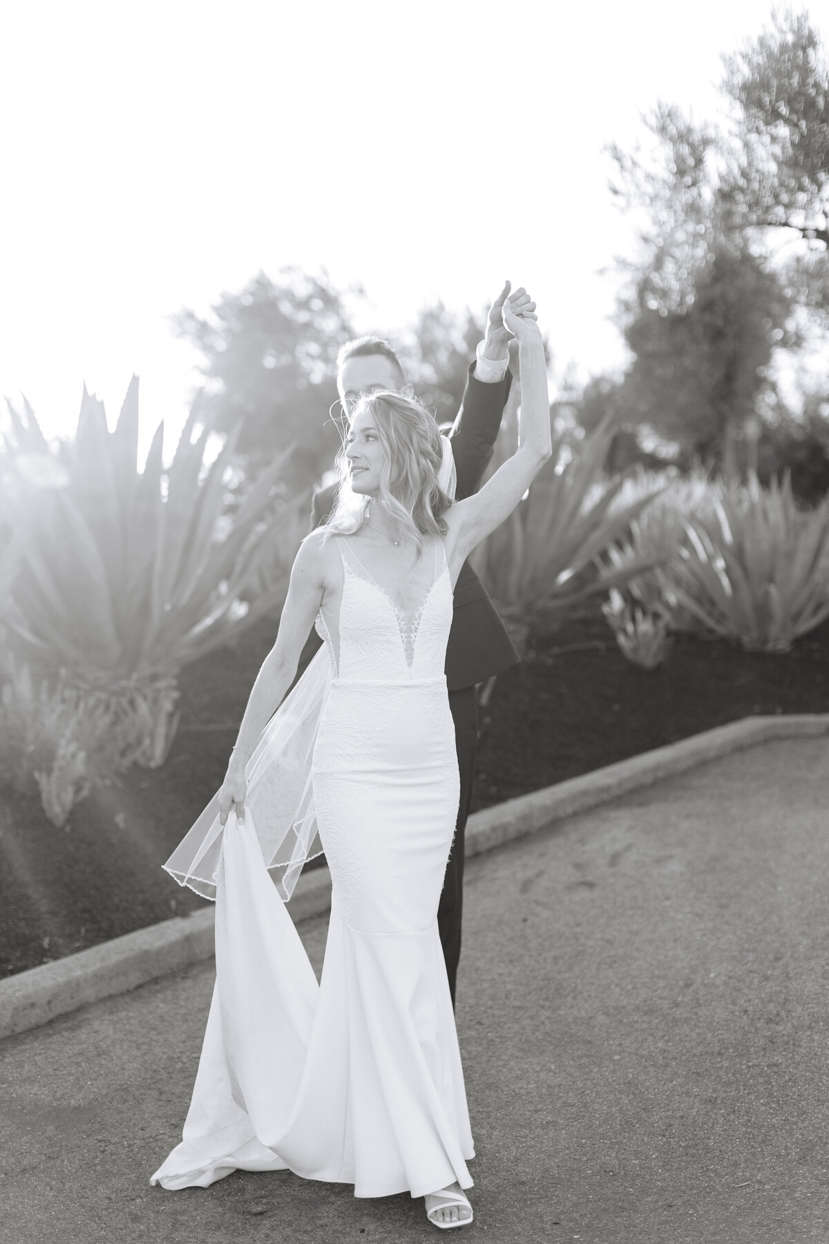 black and white image of bride and groom dancing in front of agave plants at golden hour.