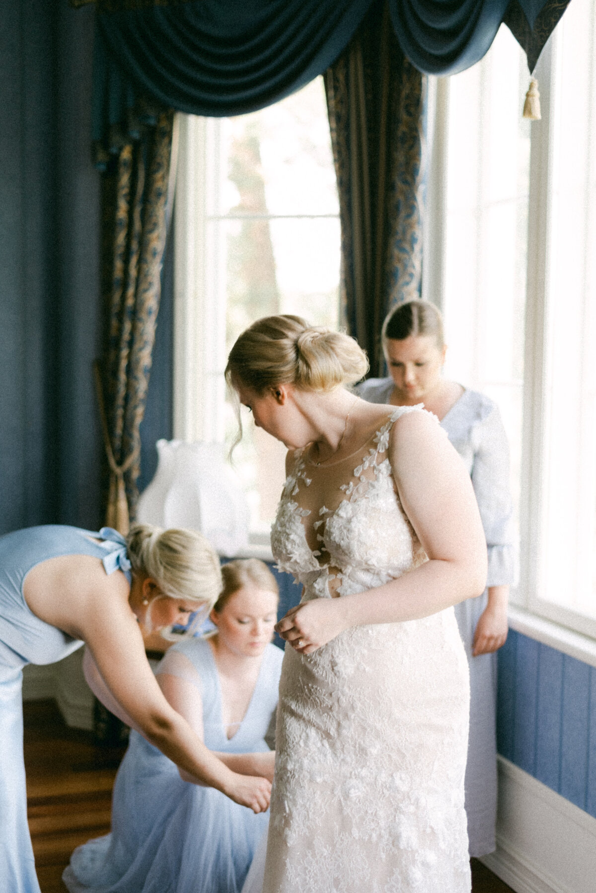 Bridesmaids are solving a problem with the wedding dress in an image photographed by wedding photographer Hannika Gabrielsson.