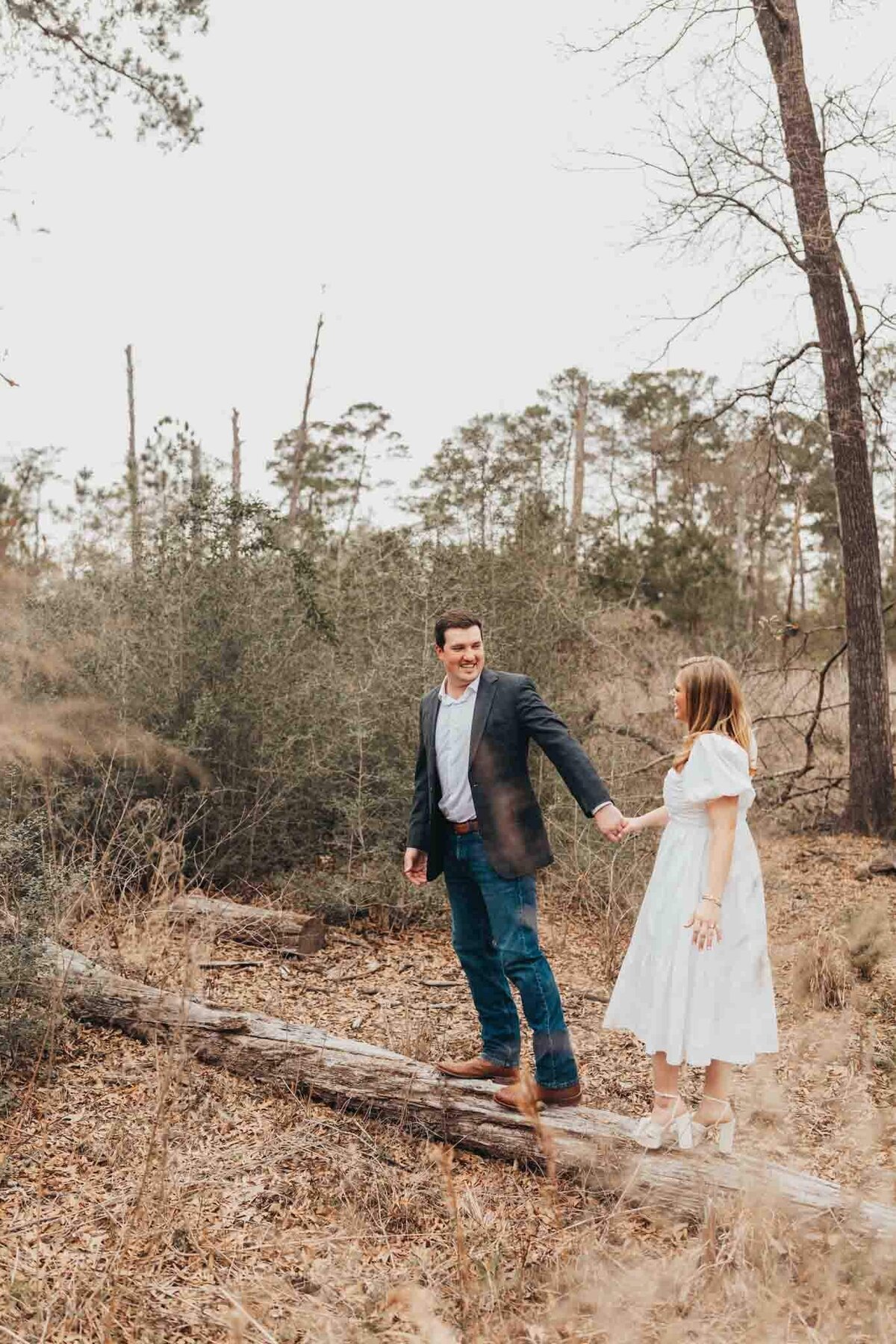 fiances hold hands while walking along a log at Houston Everglades Park, for Ally's Photography