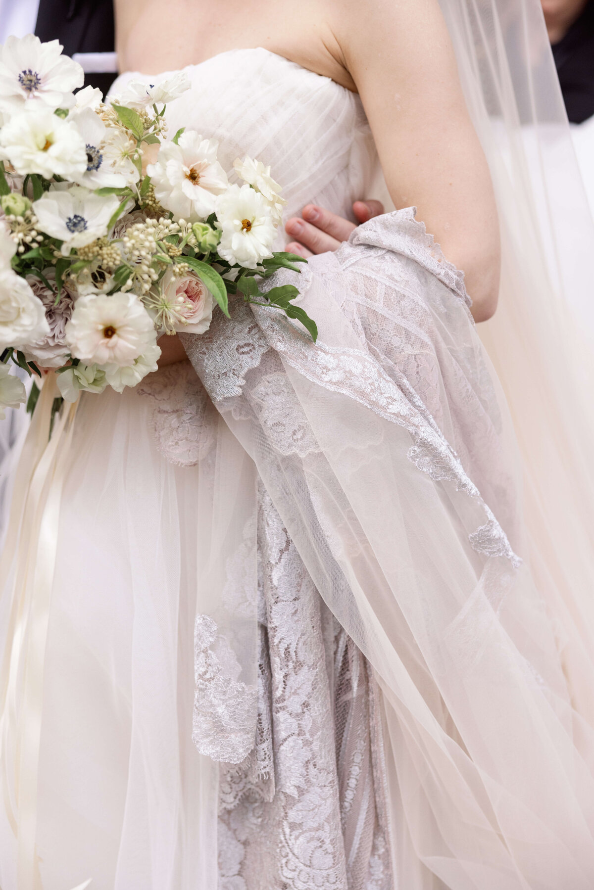 Detail of a brides tulle gown and lace veil