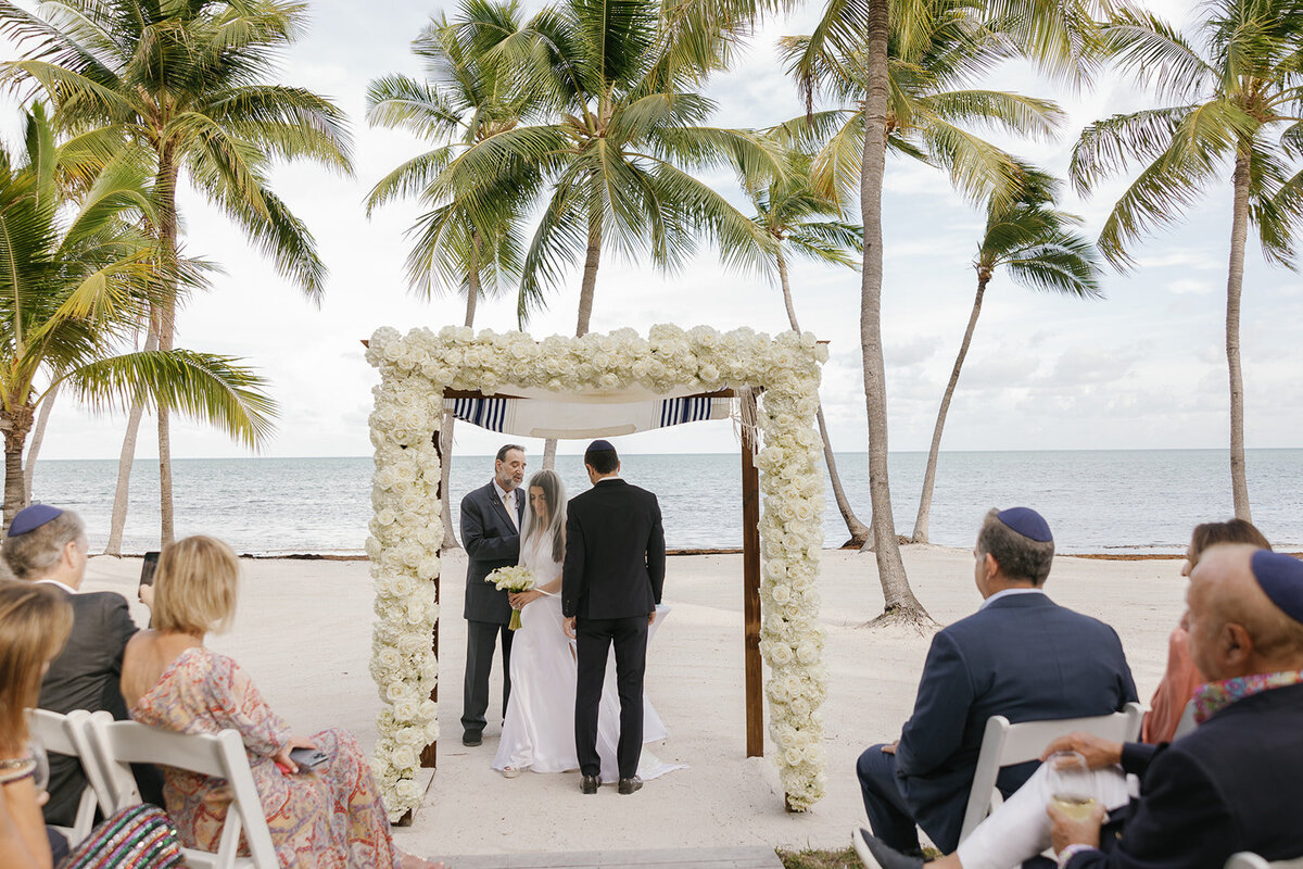 Family and friends gather to witness Minette and Evan’s wedding under the Florida sun. Destination wedding photography by Claudia Amalia.