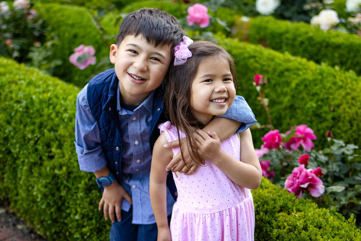 kohl mansion Burlingame Brother hugging sister while laughing together in a vibrant rose garden – playful sibling photography by Ellobelle Photography, serving the San Francisco Peninsula