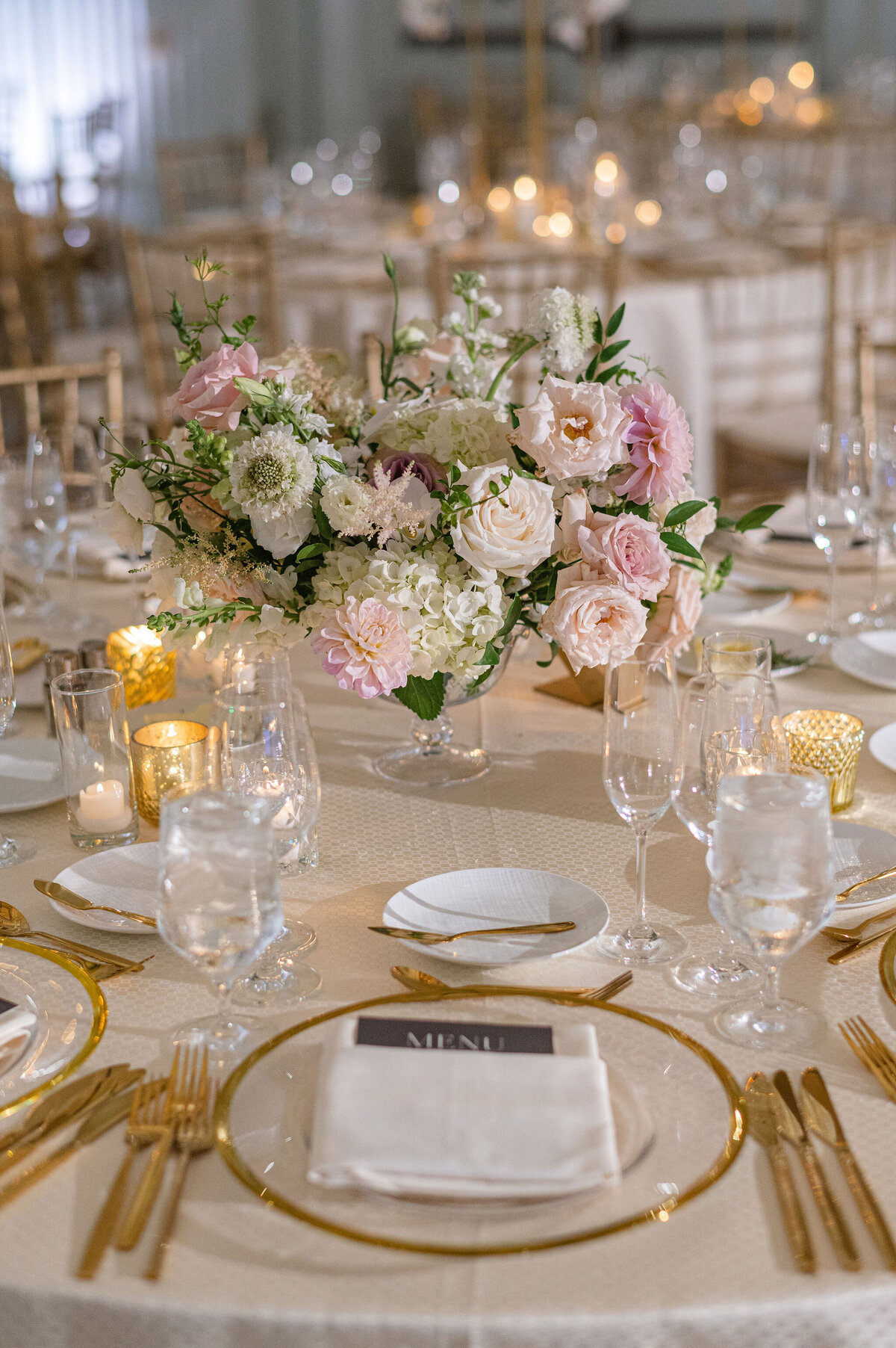 pink and white centerpiece with charger plates and gold flatware