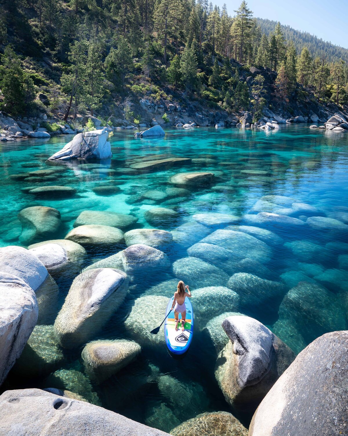 Woman standing on a paddleboard on Lake Tahoe looking at mountain