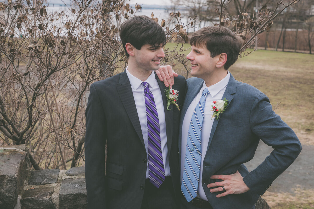 Grooms look at one another and smile.