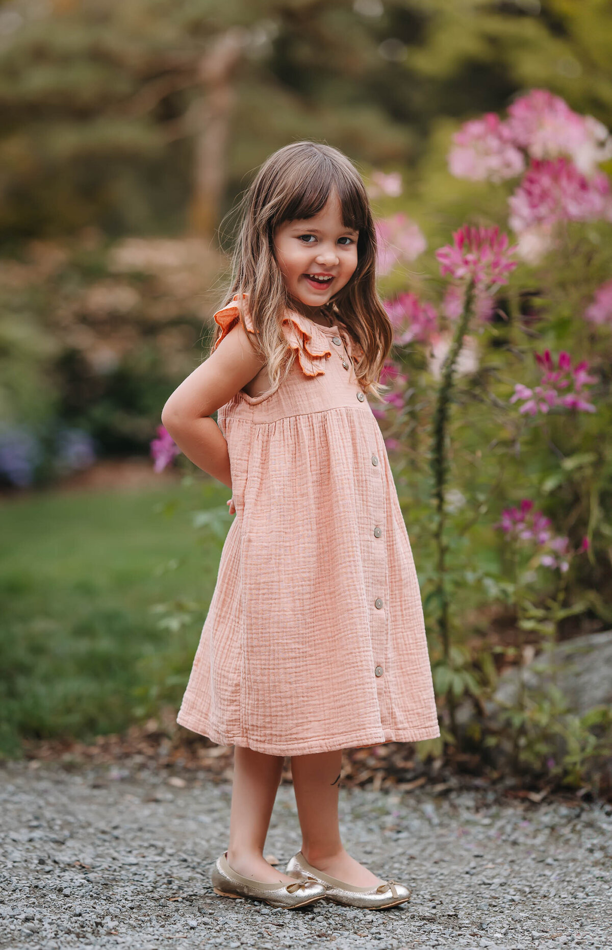Beautiful girl striking a pose with her hands behind her back, smiling playfully at the camera.