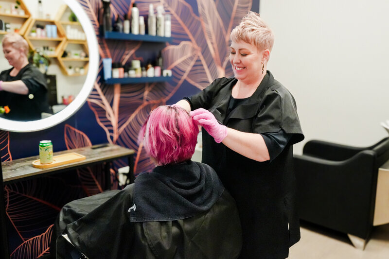 Hairstylist in salon consulting with a client with bright pink hair