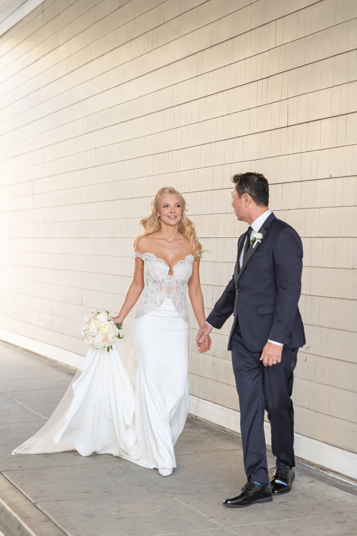 A bride and groom holding hands and walking together