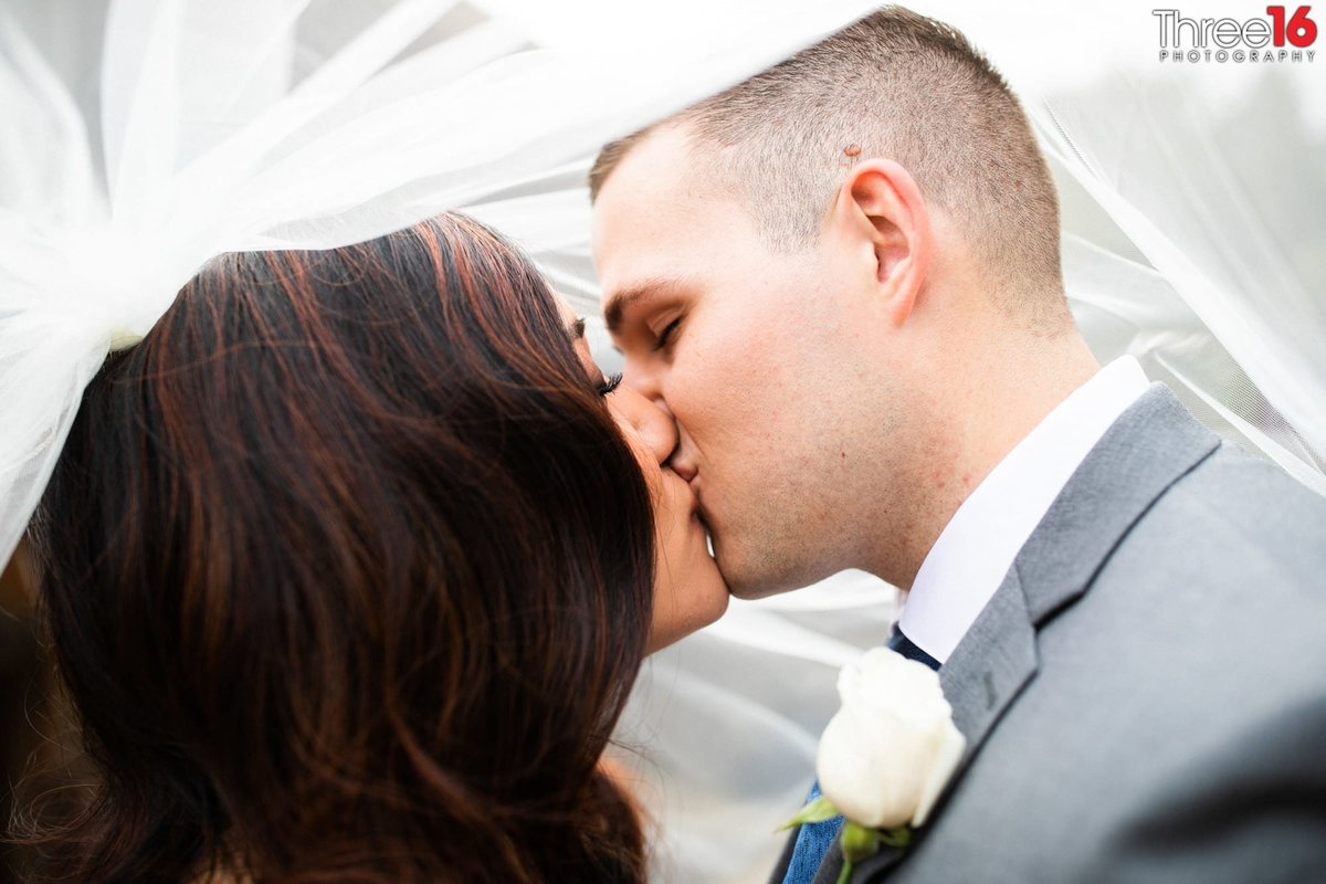 Groom and Bride share a kiss while under her veil