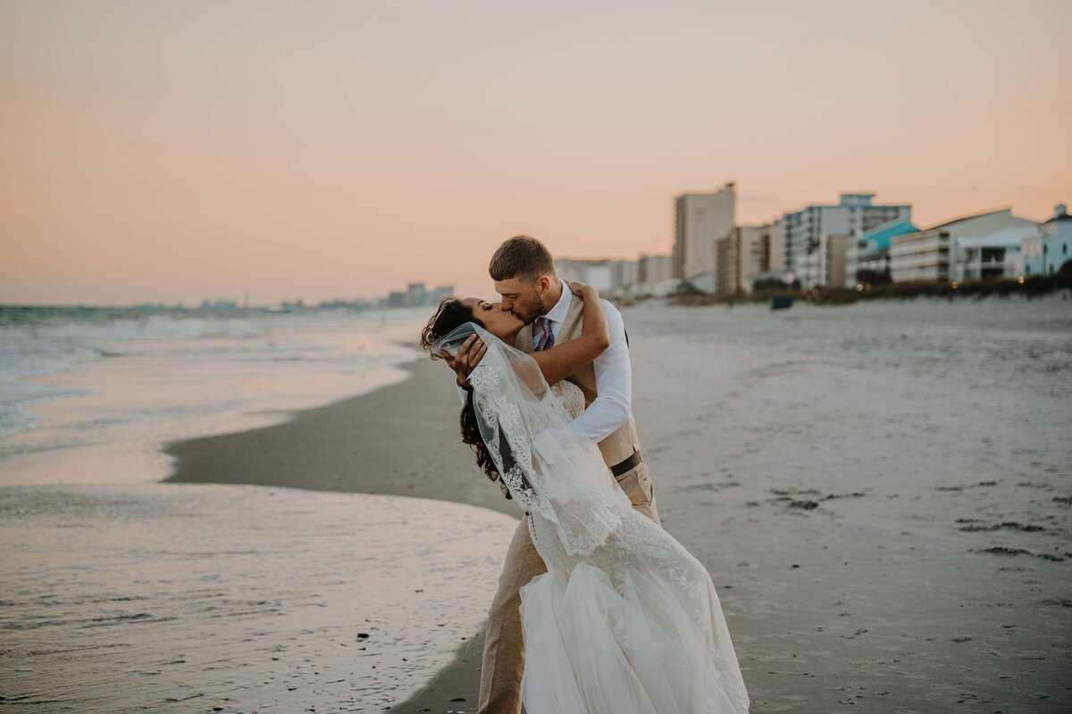 newlyweds kissing on the beach at myrtle beach in south carolina