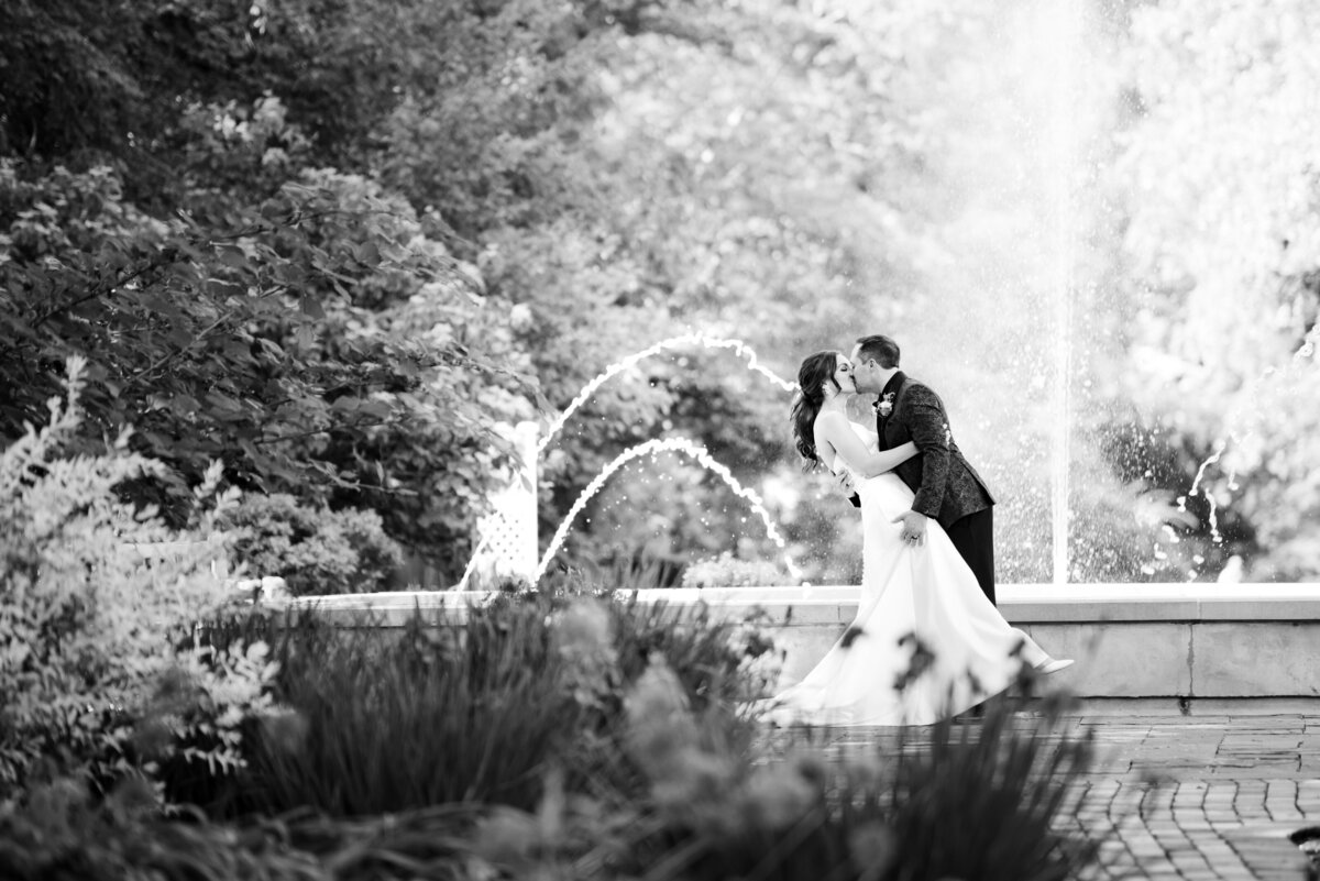 A groom dips his bride on their wedding day while celebrating in The Fellows Riverside Gardens in Ohio. Photographed by Aaron Aldhizer