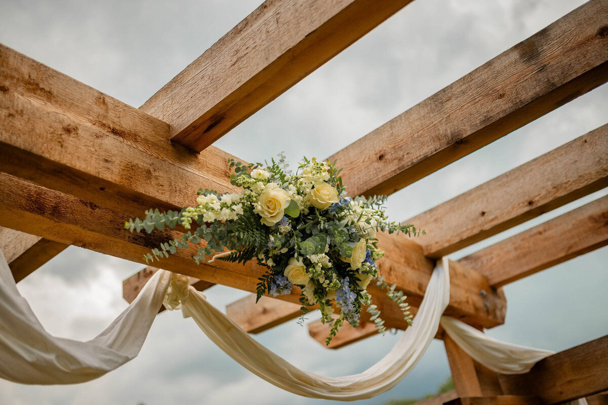 Close-up of floral arrangement and draped fabric on the pergola beams