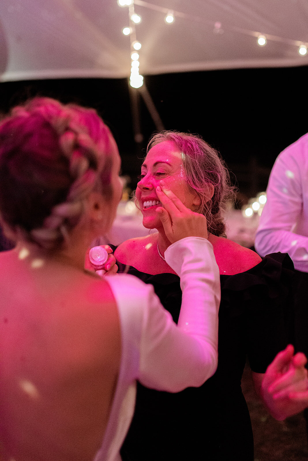 A bride applies glitter to a guests face during the reception disco dance party.