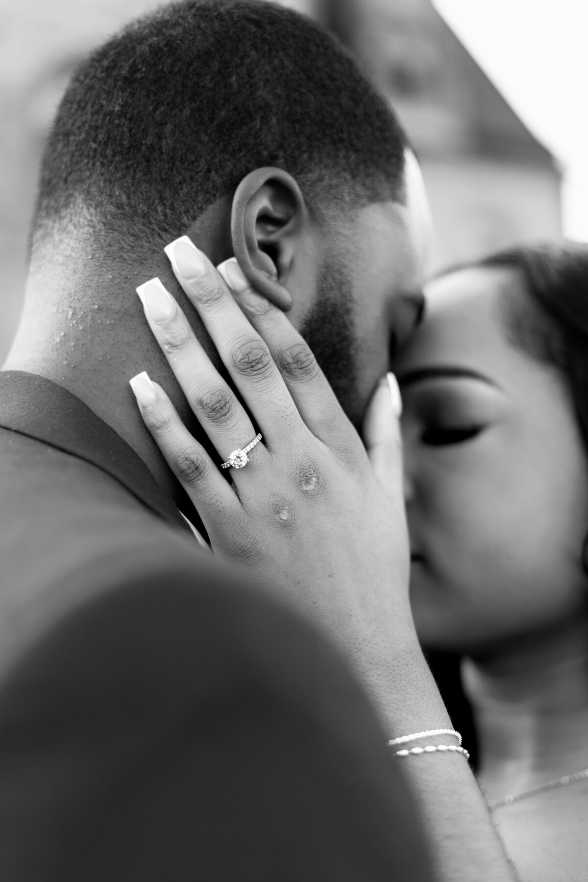 Ochre Court Mansion  | Kelsey Sheehan Photography Timeless Rhode Island Weddings | A couple shares an intimate embrace, the woman's hand with an engagement ring rests on the man's cheek. The scene is emotional and tender.