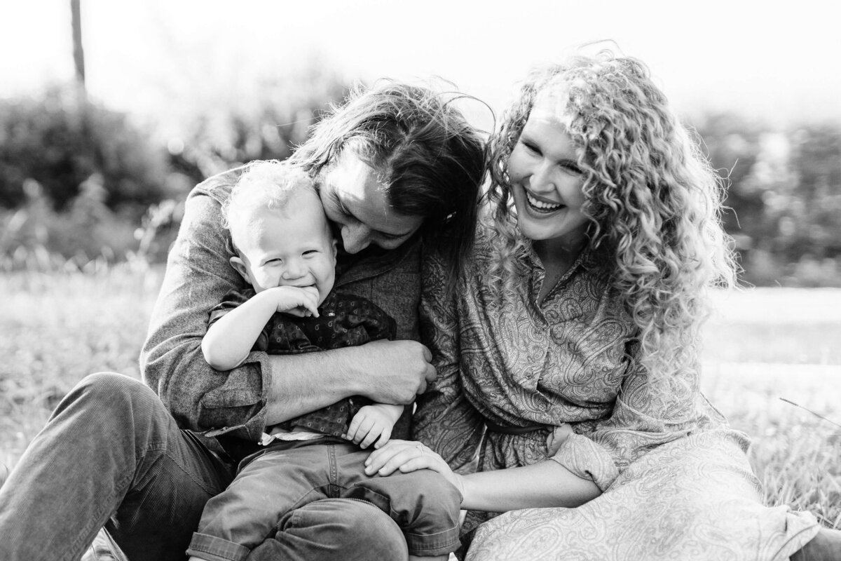 B&W photo of family laughing together at the park.