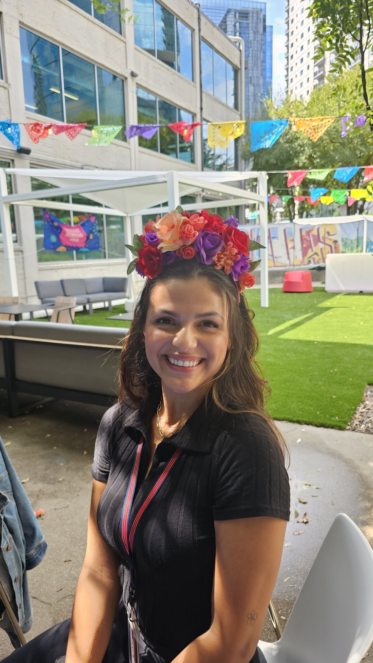 The artistry as a woman dressed in a chic black T-shirt proudly showcases her handcrafted flower wreath in our art workshop. The wreath features an array of colors, a testament to the vibrant creativity nurtured at Soleil Vida Studio.