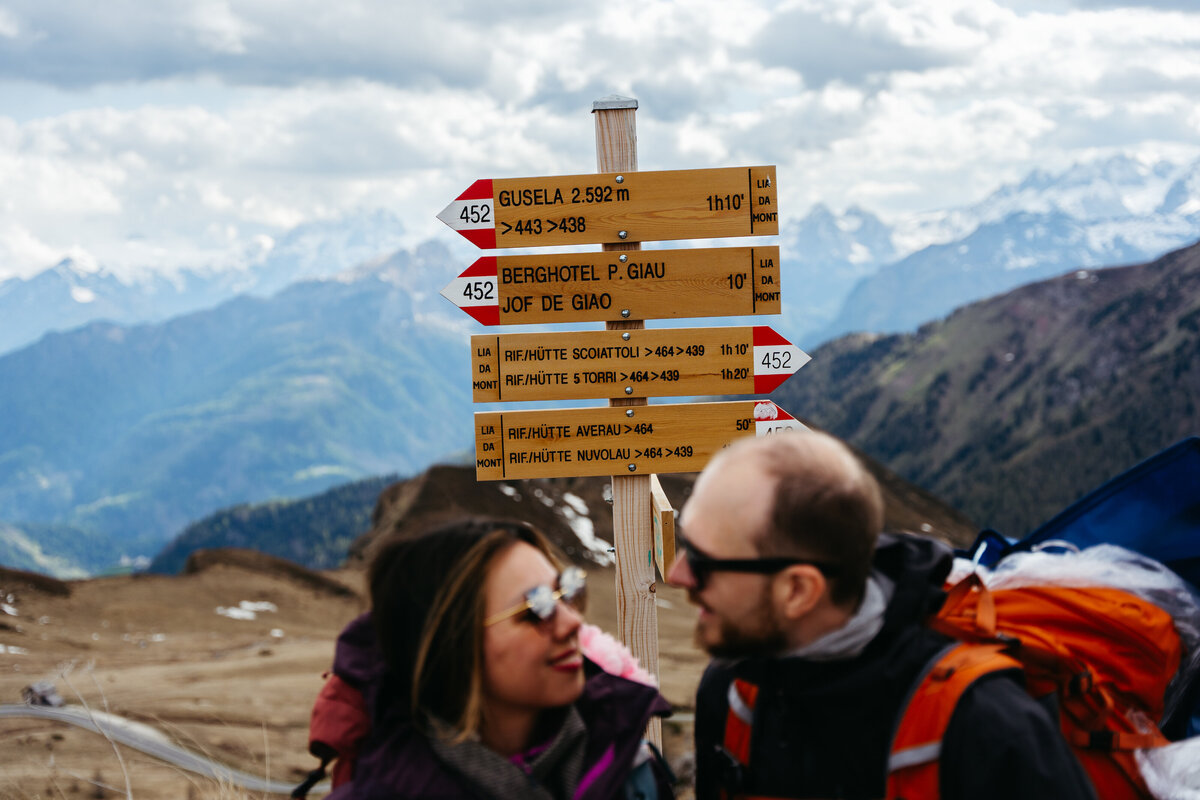 Couple standing by trail signposts during alpine hike