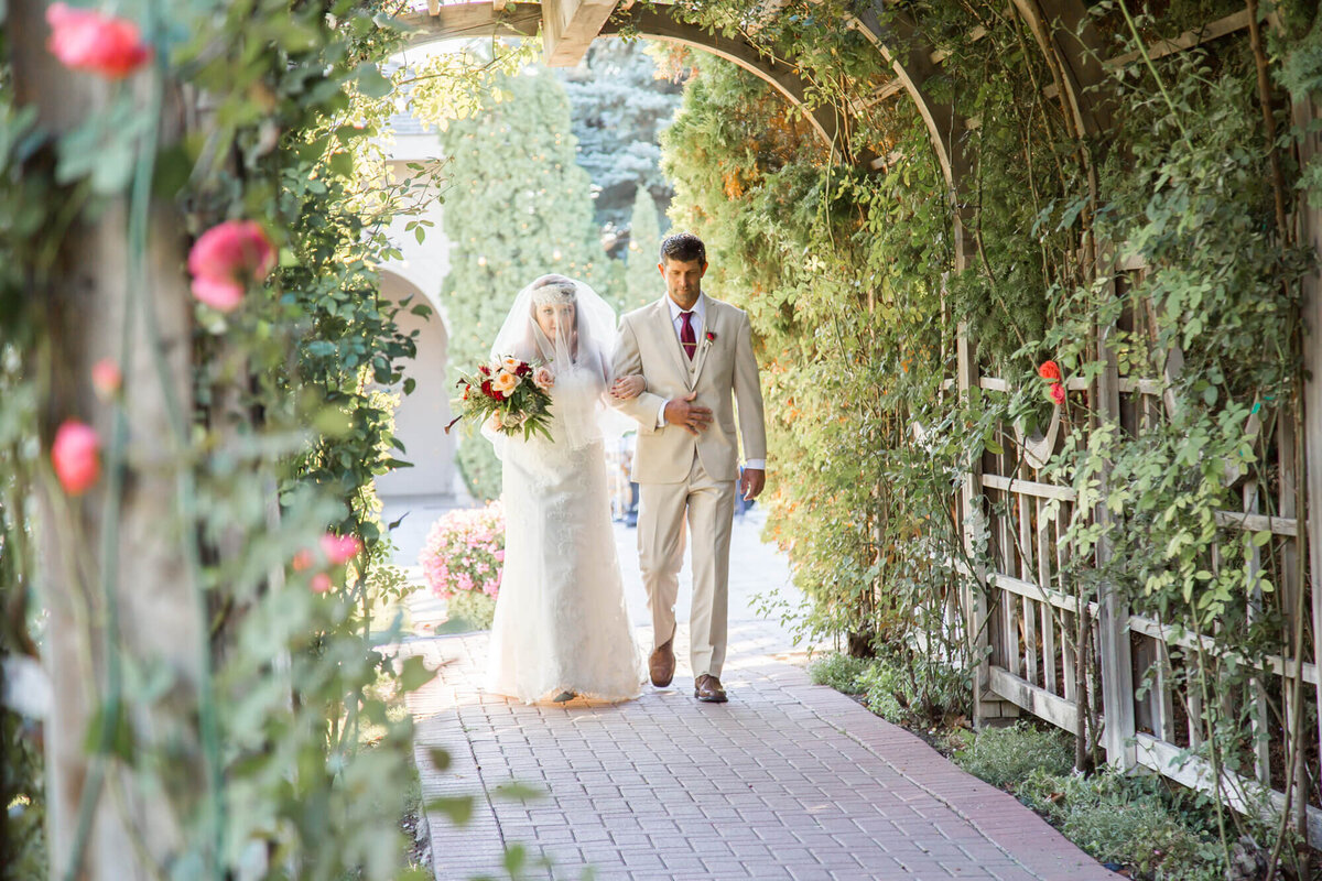 father and bride walking down the garden tunnel aisle to a classic wedding ceremony