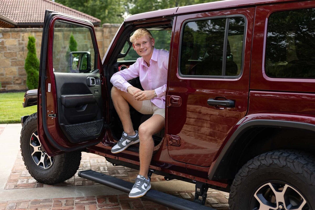 A senior guy sitting in his Jeep looking at the camera in Lawrence, KS