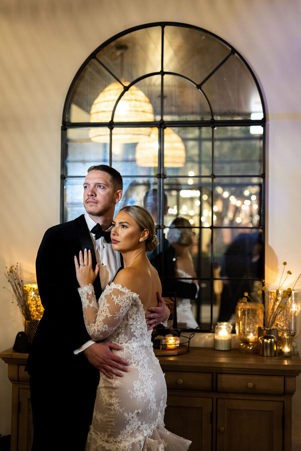 A bride and groom are posing for a picture in front of a mirror.