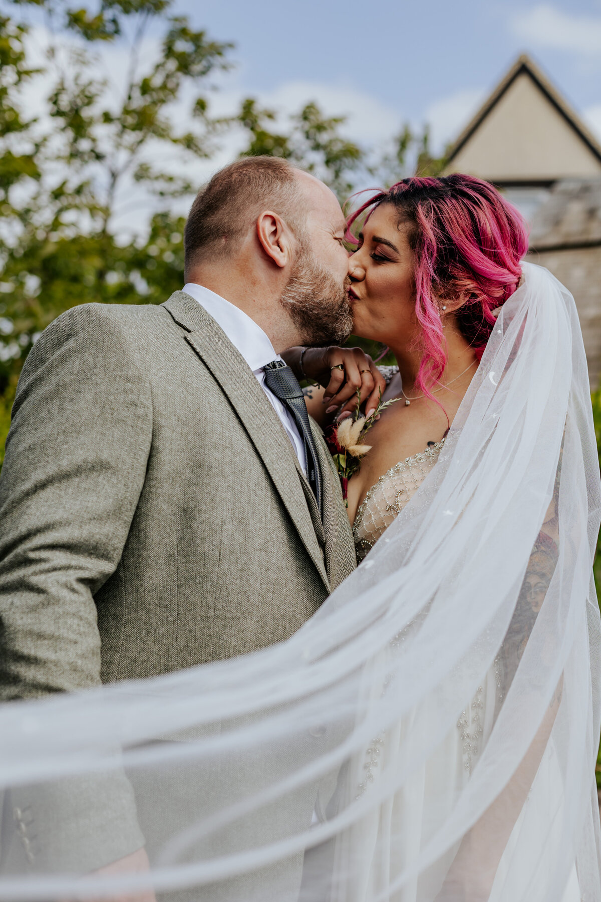 Bride and groom kiss behind a veil in the garden at The Bell in Ticehurst
