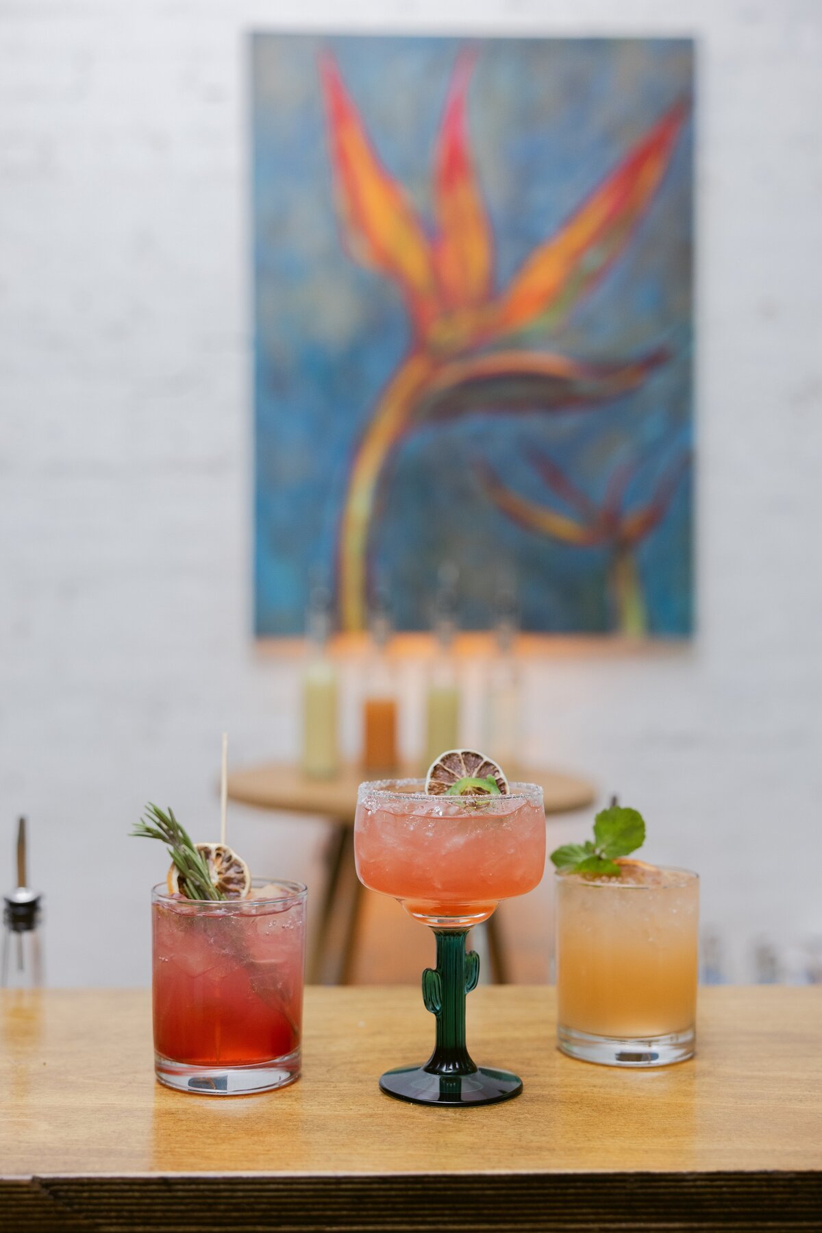 three colorful cocktails styled on bar