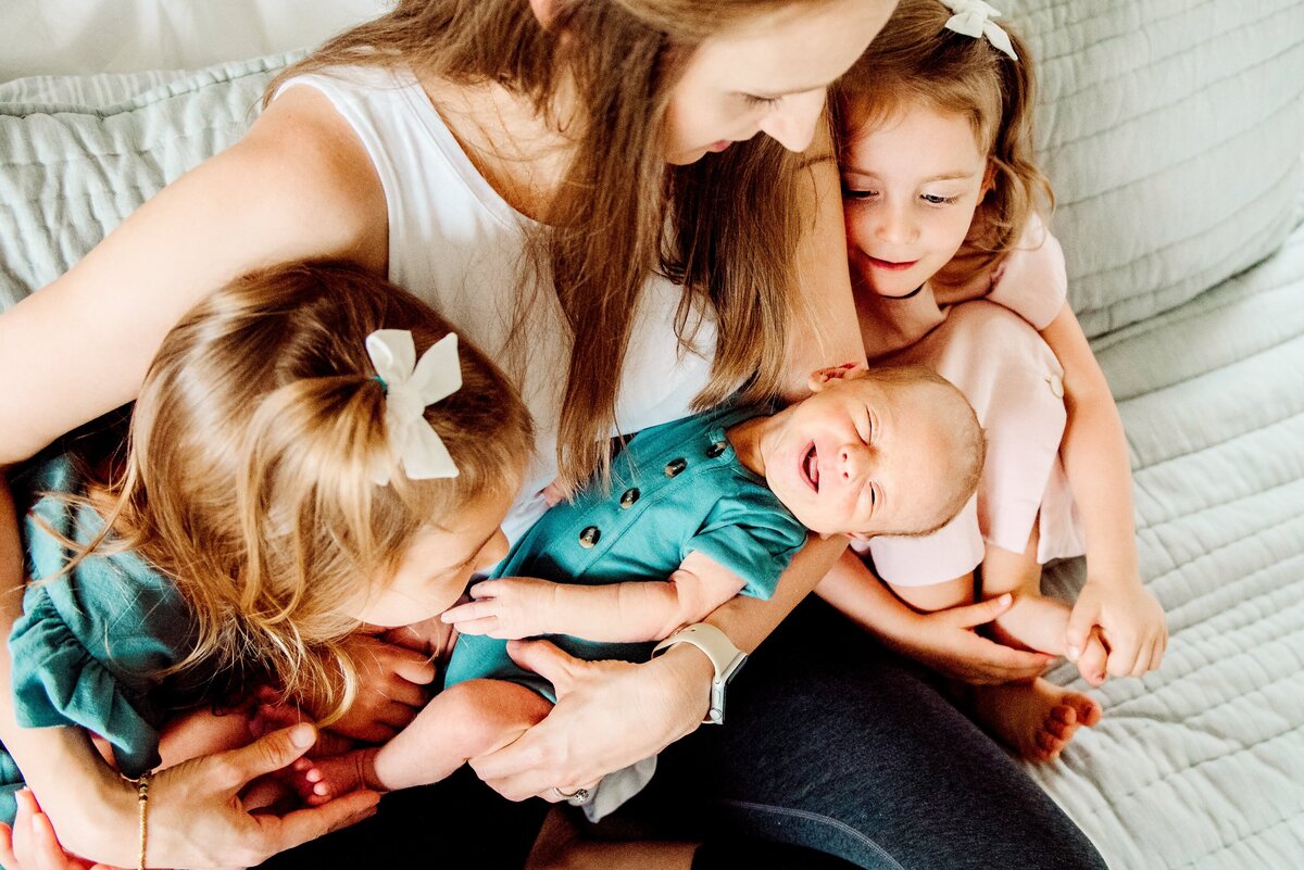 mom holding a baby with her daughters