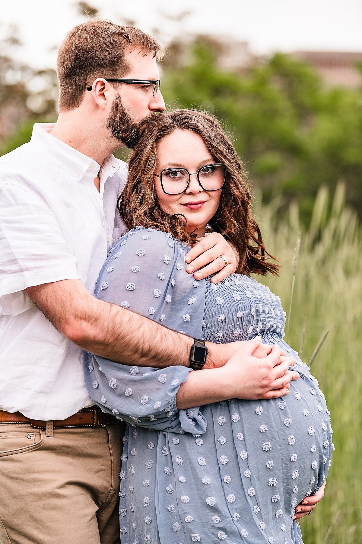 maternity pictures with husband kissing Mom on head. Mom in blue dress