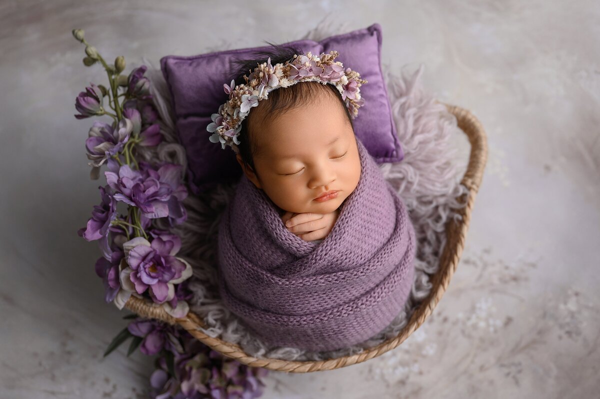 Girly newborn photoshoot with flowers in purple.