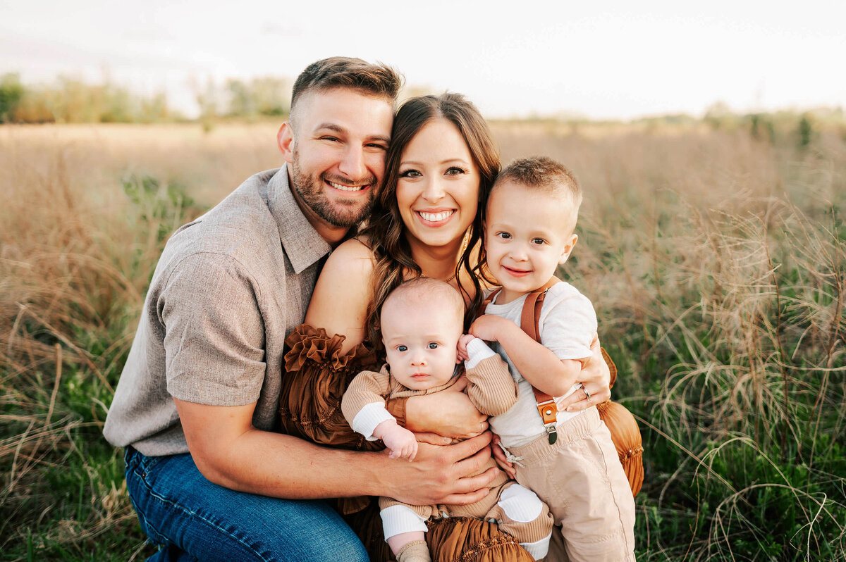 Springfield MO family photographer captures family hugging in a field smiling