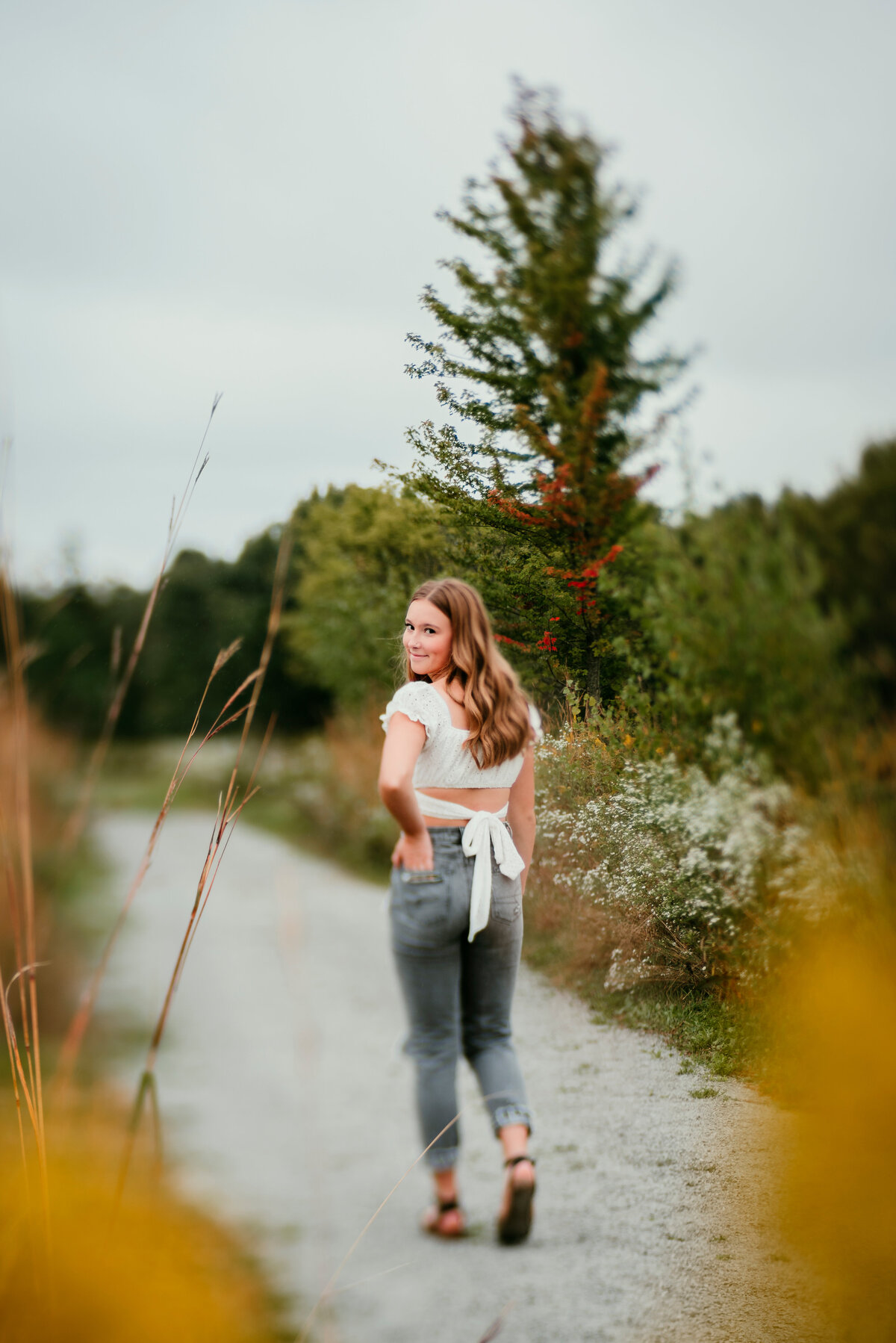 Showcase a graduate’s glamour and confidence in this unique senior portrait taken with the Lensbaby Edge 80, emphasizing their poised demeanor with a soft, artistic blur that isolates them from the bustling background.