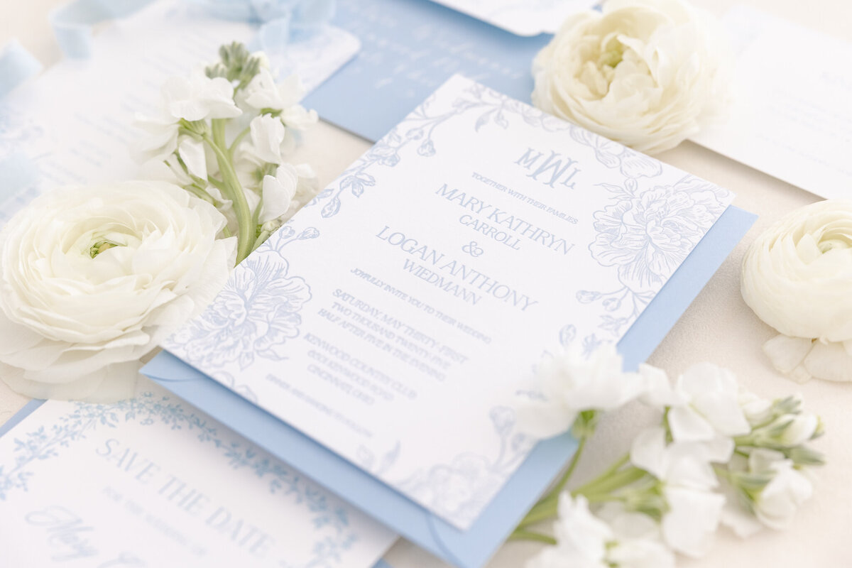 bright light and airy wedding photo of bride and groom rings and invitation