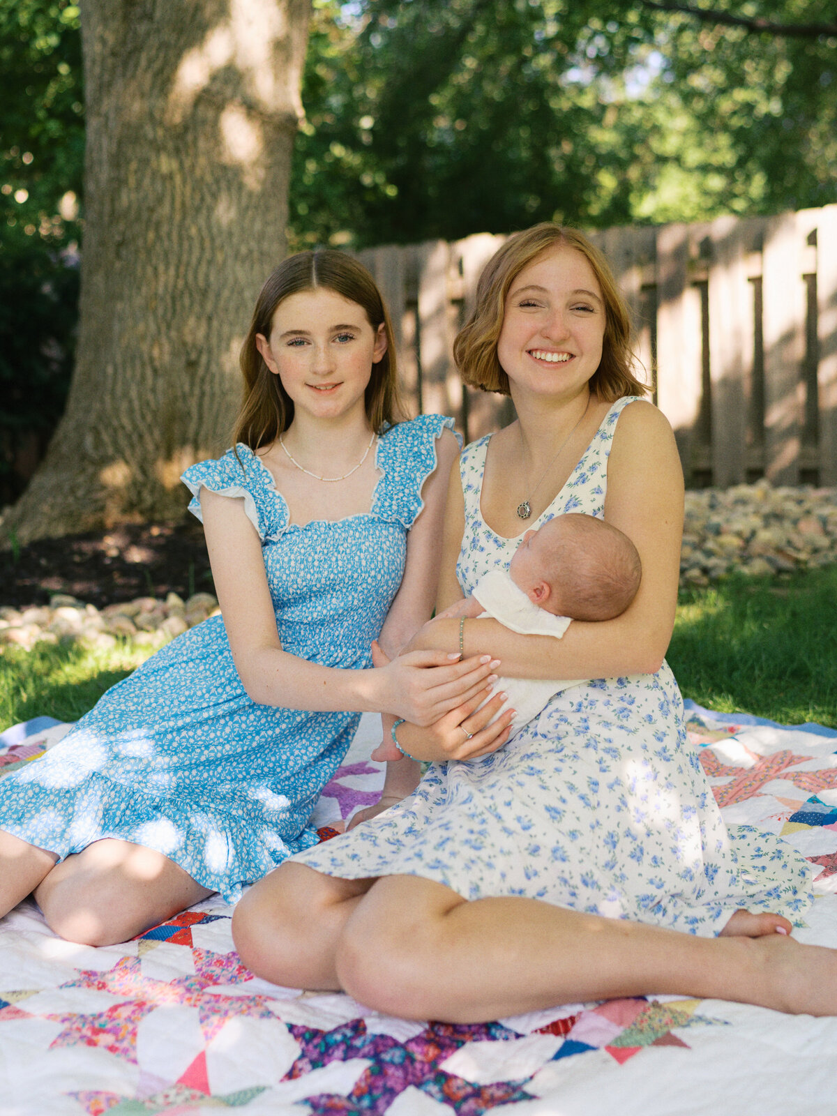 big-sisters-holding-baby-in-backyard