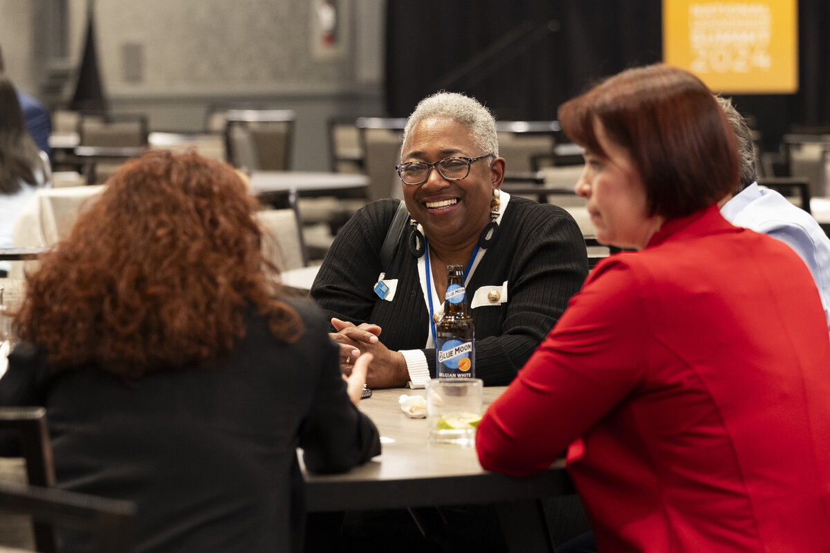Three people laugh while in conversation at a Washington DC event.