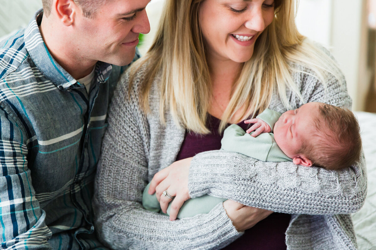 mom and dad holding and admiring newborn baby