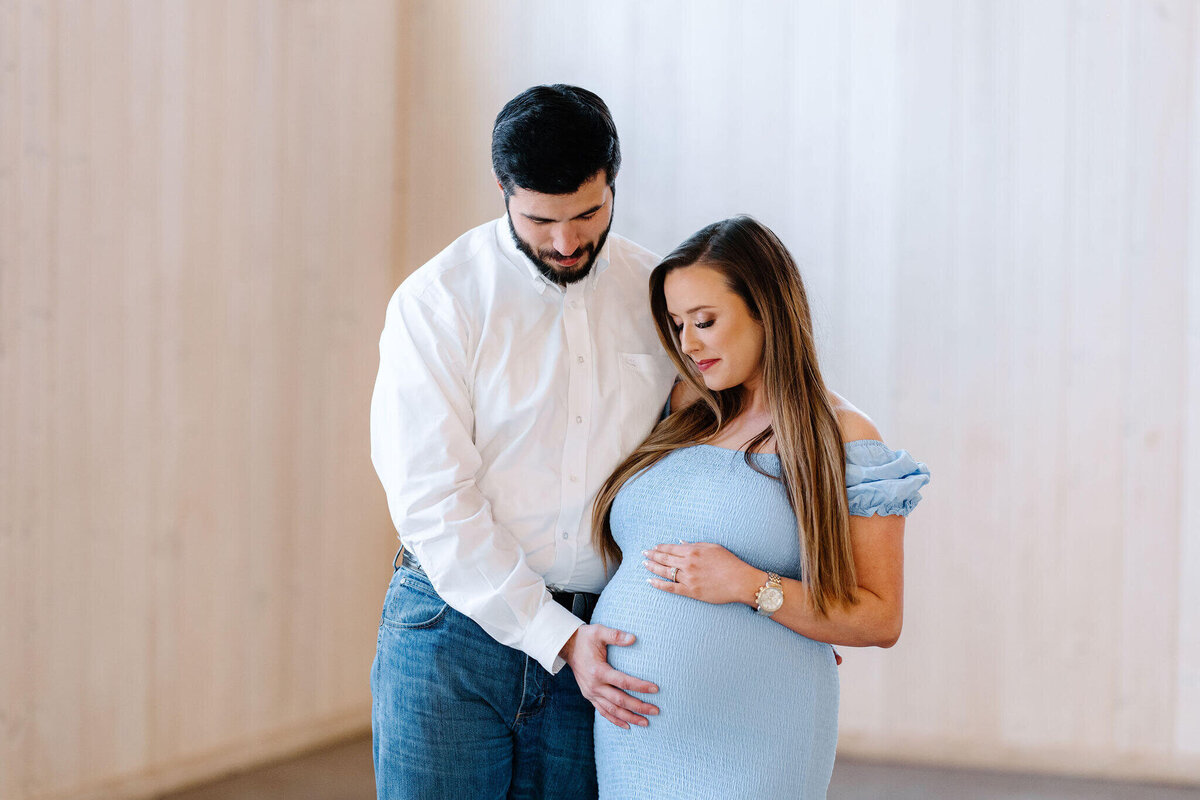 maternity picture of expecting mother standing with husband looking at baby bump