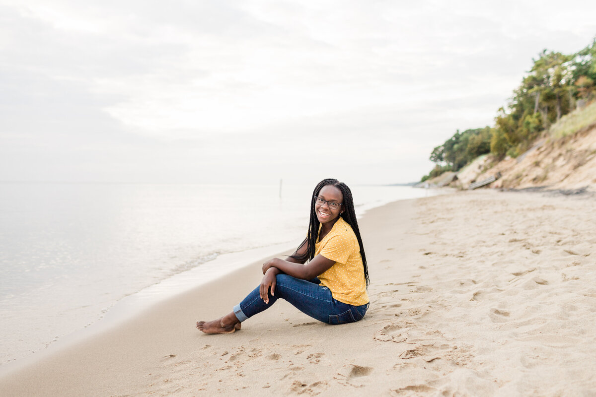 girl sitting on the beach smiling at the camera
