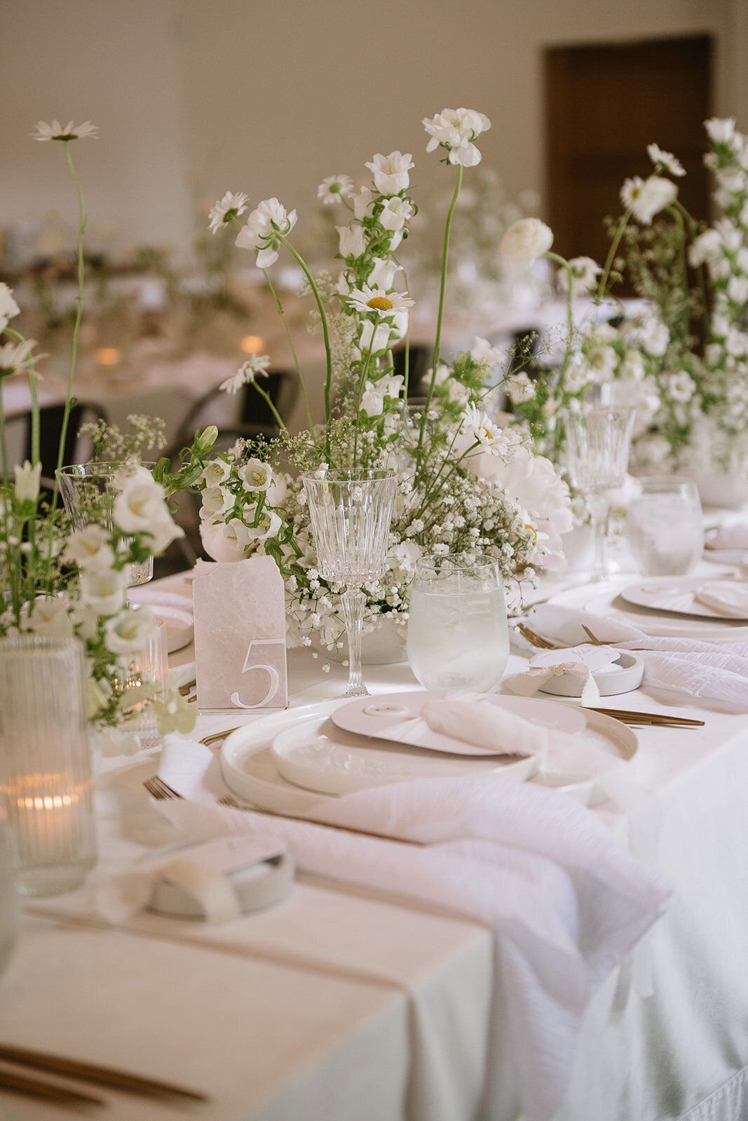 A row of modern wedding centrepieces forms a meadow of white flowers at Verger du Flanc Nord.