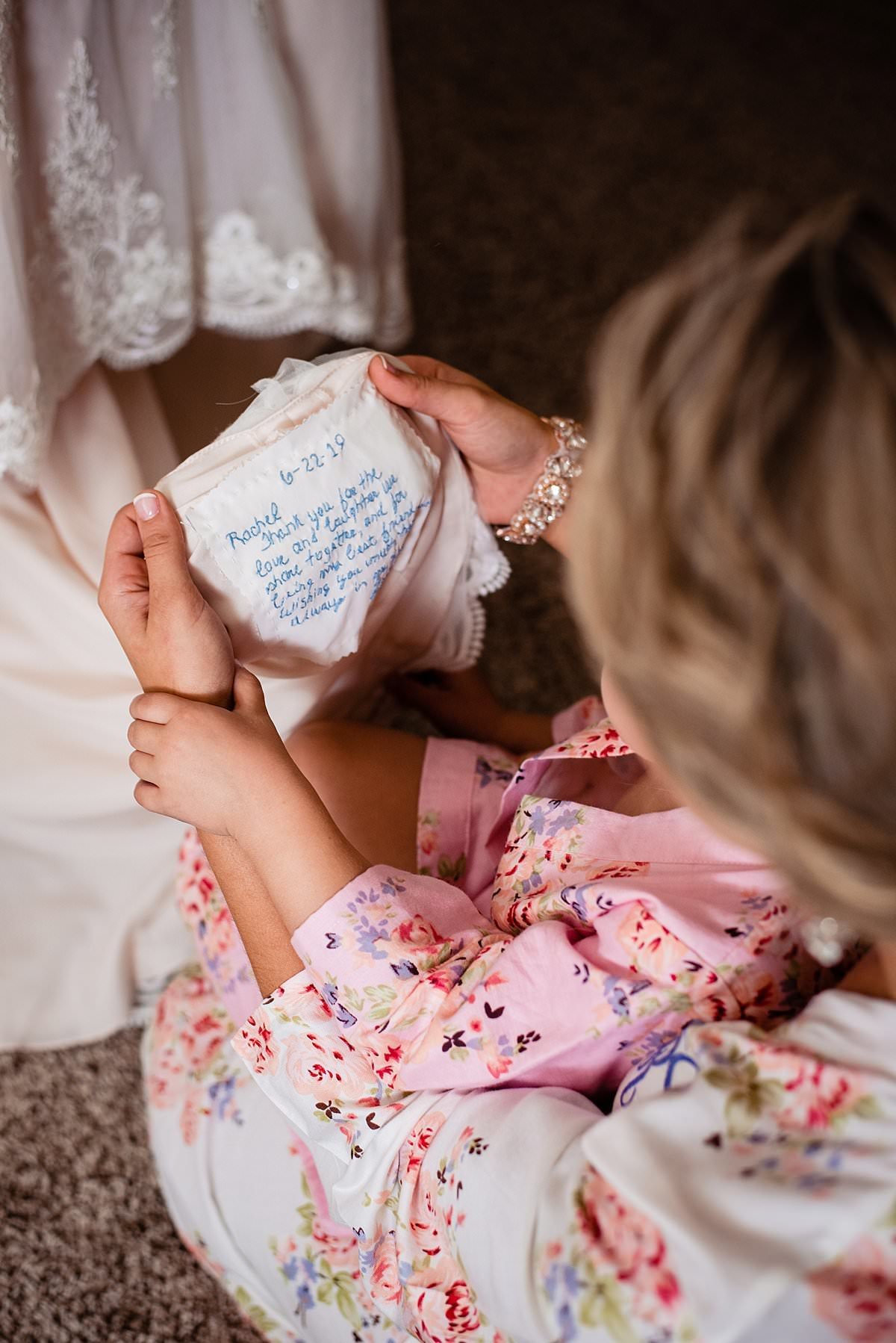 Bride showing flower girl the custom monogram patch she had sewn into the bottom of her wedding dress