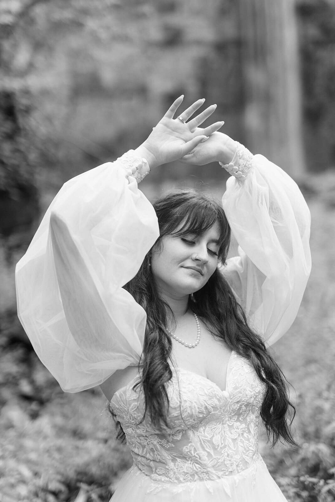 Bride with hands in the air wearing a  long sleeved dress